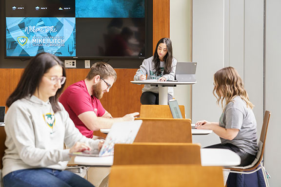 Students sitting at tables in the Mike Ilitch School of Business lobby